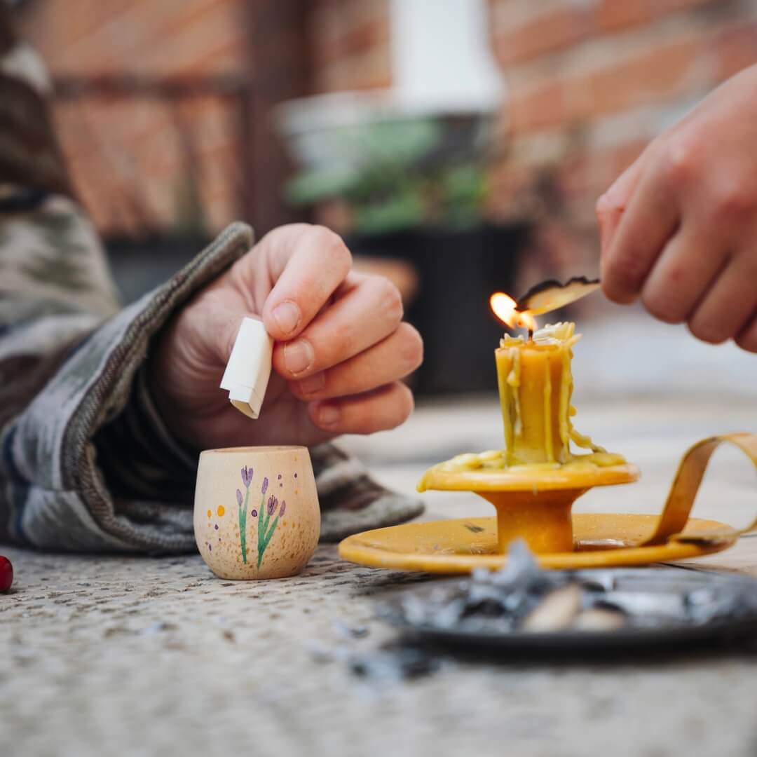 A child places a piece of paper in a wooden vessel from the Grapat 2026 Advent Calendar.